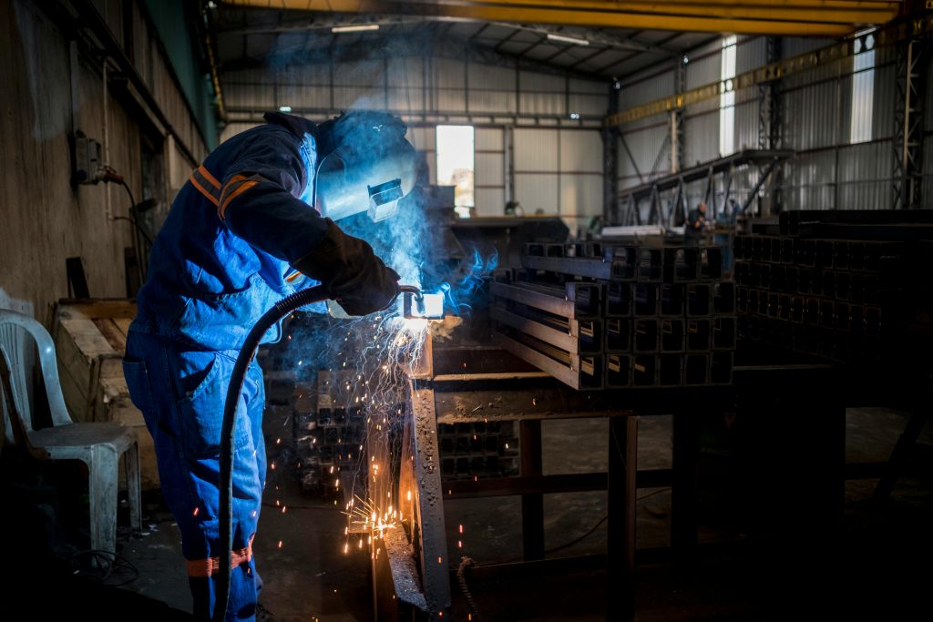 A welder at work inside a manufacturing facility in Adana, Türkiye. Sparks fly during the process.
